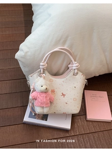 Close-up of white bucket bag with cartoon patterns and a cute pink bear plush charm