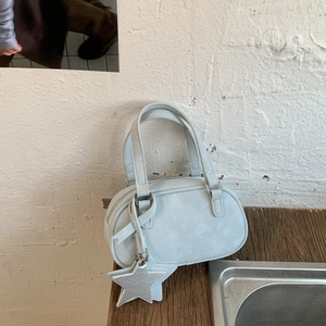 Detail of light blue mini Boston bag with fine leather texture and silver star charm