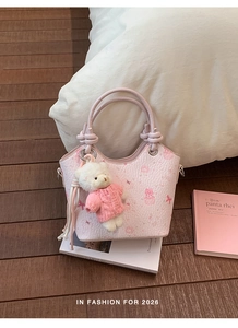 Detailed view of pink textured bucket bag with cute bear patterns and plush teddy charm