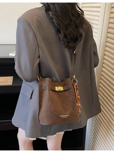 Retro dark brown matte bucket bag with gold clasp and wooden bead charm on a model