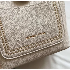Gros plan détaillé sur le cuir grainé crème avec coutures décoratives et logo doré Mandan