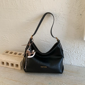 Detail of black matte leather tote bag with gold logo and wooden horse charm