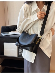 Sac seau classique en cuir noir avec ferrures dorées et bandoulière large en nylon au bureau