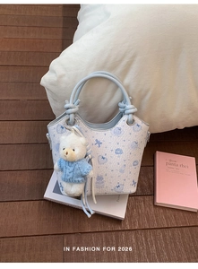 Detail of white bucket bag with bunny prints and cute bear charm in a lifestyle setting