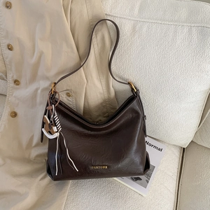 Close-up of a brown leather shoulder bag with a horse charm and metal brand logo