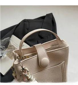 Détail du sac seau en cuir crème avec boucle ronde en métal et ornement de corde tressée