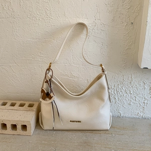 Macro view of cream leather tote bag with gold logo and wooden horse charm detail