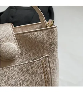 Détail d'un sac seau en cuir beige grainé avec finition texturée et détails métalliques dorés