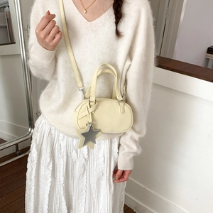 Detail of light yellow leather Boston bag with star charm and adjustable shoulder strap