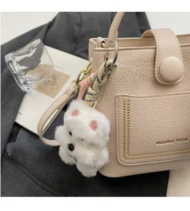 Détail du sac à main en cuir beige avec logo doré et charmant chiot en peluche