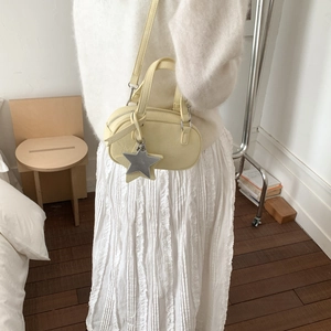 Pale yellow mini boston bag with star charm styled with soft cream knitwear and long skirt