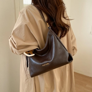 Detail of dark brown leather tote bag with gold logo and white stitching craftsmanship