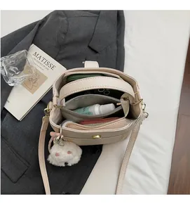 Intérieur spacieux d'un sac seau en cuir grainé crème montrant les essentiels quotidiens
