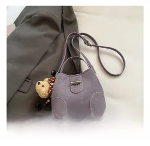Detail of purple bucket bag with metal twist lock and cute teddy bear charm pendant