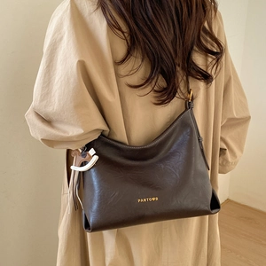 Detail of dark brown leather hobo bag with logo engraving and contrast horse charm accessory