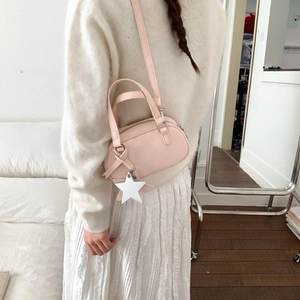 Rear view of a model wearing a small pink Boston bag with a white star pendant
