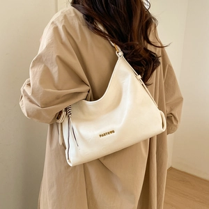 Close-up of cream Pantoor tote bag featuring gold logo and woven side detailing