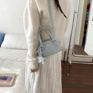 Close-up of light blue mini Boston bag featuring a white star charm and leather handles