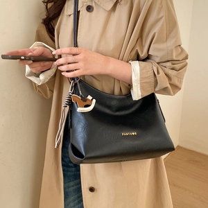 Close-up of black tote bag with gold lettering and decorative horse charm detail