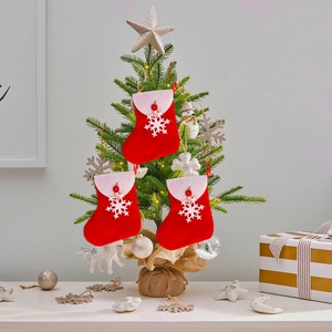 Three red Christmas stockings with white snowflakes hanging on a decorated festive tree