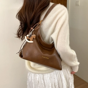 Detail of dark brown leather Hobo bag featuring gold logo and horse-shaped charm
