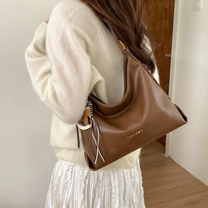 Side view of dark brown leather hobo bag worn by model with gold buckle and logo