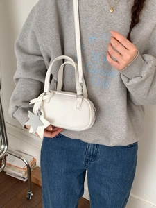 Modern creamy white Boston bag with star charms shown in a stylish crossbody wear profile