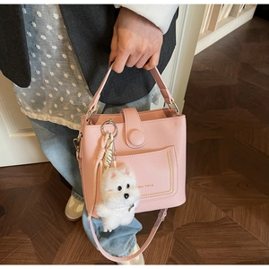 Détail du sac seau en cuir litchi rose avec lettrage doré et breloque petit chien