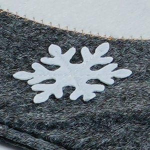 Macro shot of grey fabric with a white embroidered snowflake for Christmas decor