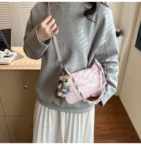 Detail of light pink small square bag with cute bear charm and woven top handle strap