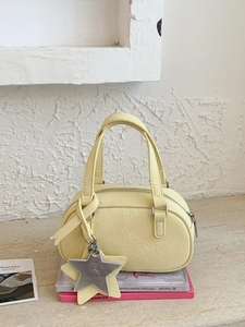 Light yellow mini Boston handbag with star charm on stone surface background