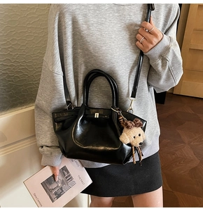 Details der schwarzen Kunstledertasche mit Leoparden-Hundeanhänger und Metallschnalle