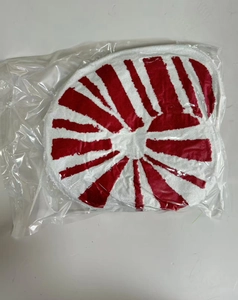 Detail eines runden rot-weiß gestreiften Plüschkissens in klarer Schutzverpackung