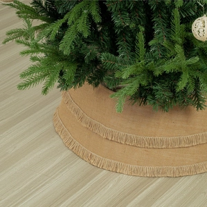 Detail of burlap Christmas tree collar featuring a two-tier fringe on light wood floor