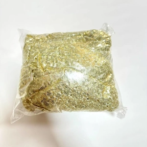 Close-up of shiny gold sequins material inside a clear plastic protective packaging