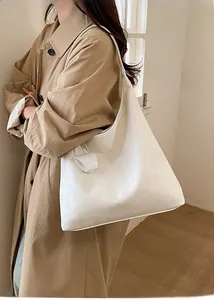 Dettaglio della borsa hobo bianca capiente in pelle abbinata a un classico trench kaki
