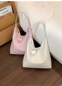 Dettaglio di grandi borse tote rosa e beige con pochette coordinata in una stanza accogliente