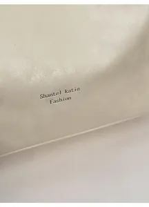 Detail of soft creamy white textured leather tote bag with embossed Shantel Katie logo