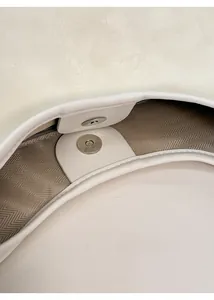 Detail of magnetic snap closure and textured fabric lining on beige tote bag