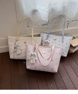 Close-up of cute cartoon tote bags in beige, blue, and pink with plush bear charms