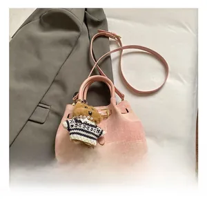 Detailansicht der rosa Stoff-Eimertasche mit Bärenanhänger und Leder-Schultergurt
