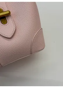 Close-up of pink lychee grain leather handbag featuring a vintage gold metal twist lock