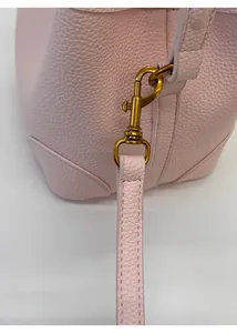 Macro shot of vintage gold buckle and lychee grain leather on light pink bucket bag