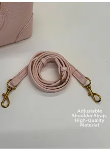 Detail of adjustable pink leather shoulder strap with gold buckle and pebble texture