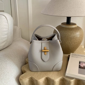 Chic light gray lychee pattern leather bucket bag with gold metal clasp on wooden table