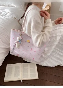 Detail of pink embossed tote bag with cartoon bear prints and cute plush charm on shoulder