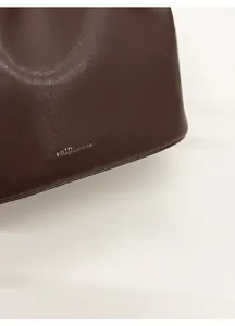 Détail du marquage doré sur le cuir texturé marron foncé d'un sac seau élégant