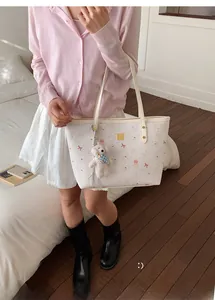 Detailed view of white tote bag featuring pink bow patterns and a plush dog charm