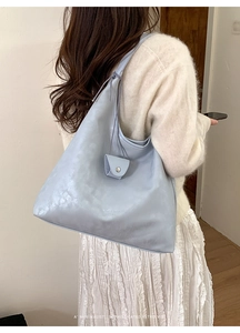 Detail view of light blue hobo tote bag with mini purse charm and smooth leather texture