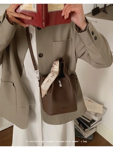 Detail of lychee pattern leather bucket bag with silk scarf on handle and silver lock